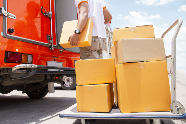 送货员带着包裹盒子和手推车给客户送货图片下载