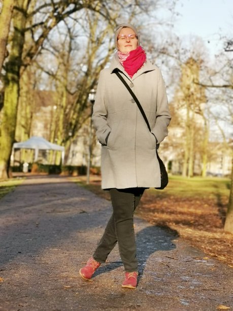 年轻女子一边在公园里散步，一边享受着冬日的温暖图片下载