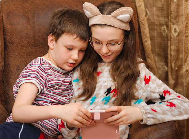 孩子们拿着智能手机，看着它图片下载