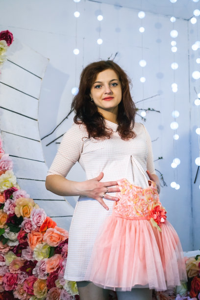 年轻的孕妇抱着小女婴的衣服图片下载