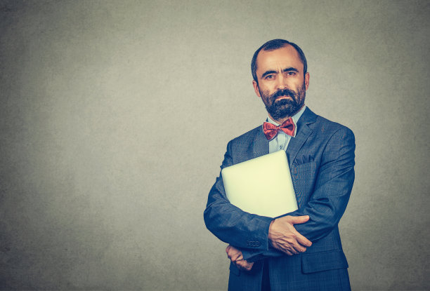 穿着商务装的男人拿着笔记本电脑，灰色的衣服看起来很严肃图片下载