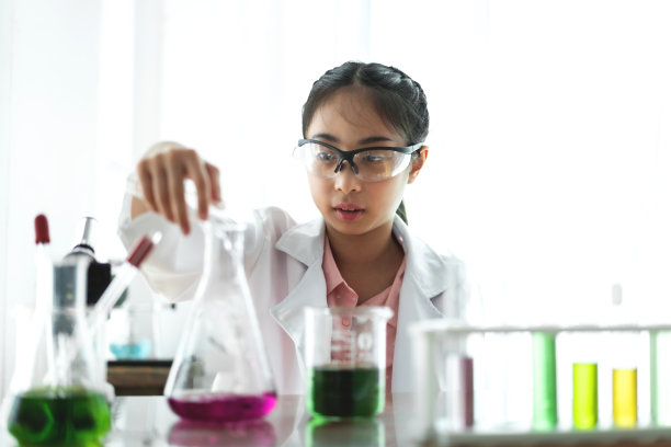 科学课上，十几岁的女学生手里拿着试管在桌子上学习做化学实验。教育的概念图片下载