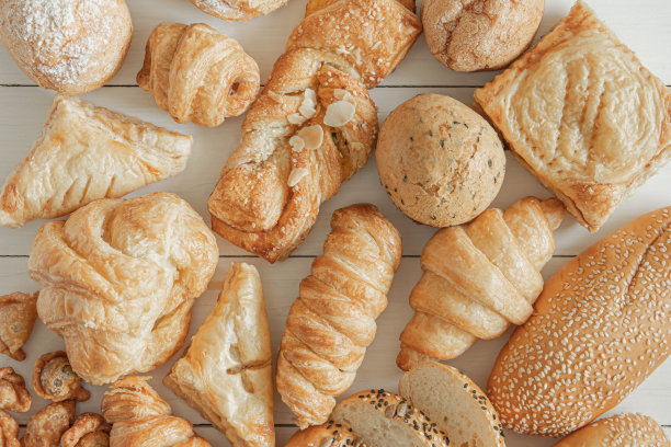 新鲜香烤面包，派，面包卷和白芝麻木桌背景，俯视图图片下载