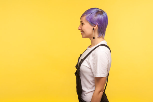 侧视图肖像快乐美丽的潮女人微笑着看拷贝空间。黄色背景，工作室拍摄图片下载