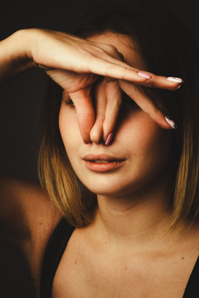 肖像女孩的黑色背景，剪辑。用手指捏住鼻子。坏气味的概念，坏空气的生态。素材图片