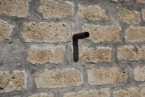 生锈的铁管和它的影子在石墙上图片下载