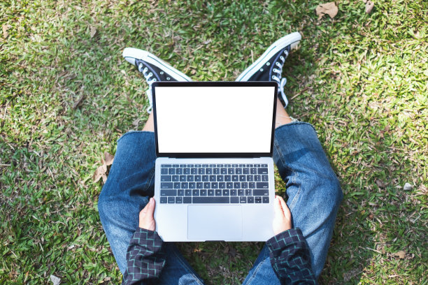 一个女人在笔记本电脑上使用和打字，白色的屏幕，坐在户外，以自然为背景图片下载
