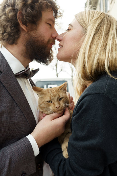 一对恩爱的夫妇，一头长发，一头卷发的男人和一只红猫站在街上图片下载