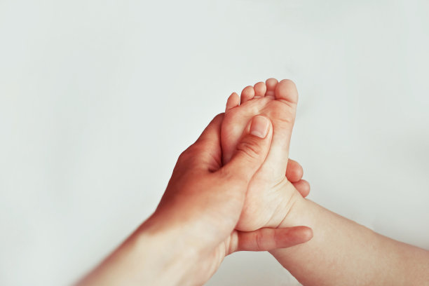 女性用双手给新生儿做足底按摩。图片下载