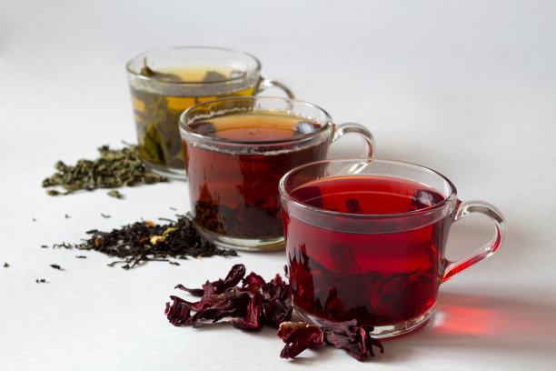 三个杯子，上面有黑茶、红茶和绿茶，白底上有干茶叶。红热芙蓉干花茶。健康的生活方式。绿色的热茶。黑色的热茶。热饮料。图片下载