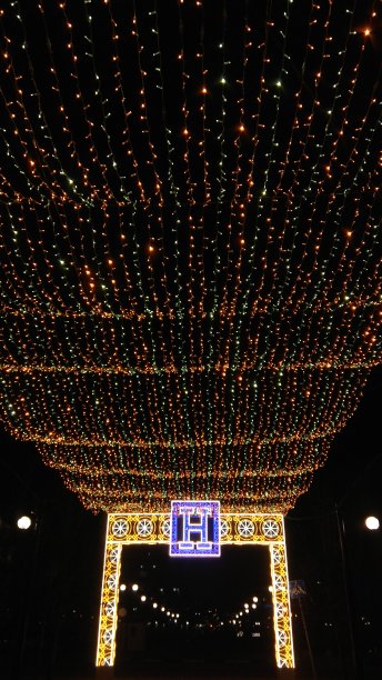 新年(圣诞)黄绿仙子串彩灯。华丽的，黄色和白色灯光矩形拱门与蓝色灯光大写字母H在中间。图片下载