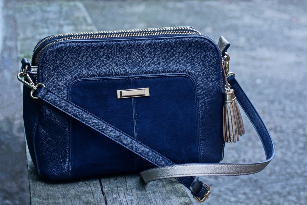 木桌上放着一个蓝色的皮革和绒面革包图片下载