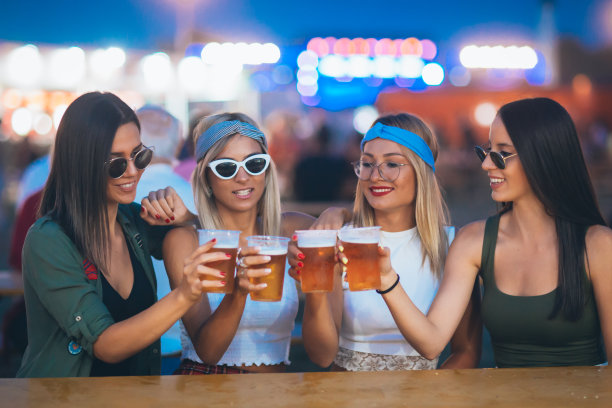 在音乐节上，女性朋友们坐在一起喝着啤酒欢呼图片下载