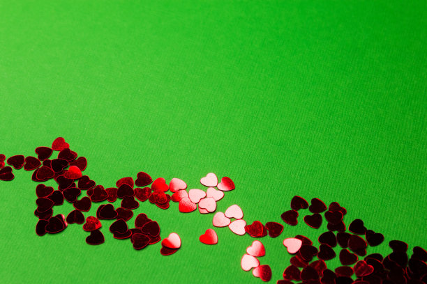 闪闪发光的心形在绿色背景上的红色可以用作卡片背景或情人节墙纸图片下载