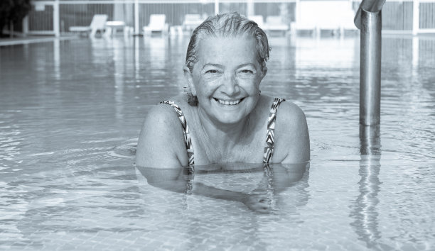 一个喜欢游泳的迷人的老女人。大的笑容。室外游泳池，蓝色的水。健康的活动来保持健康。在热带地区隐居图片下载