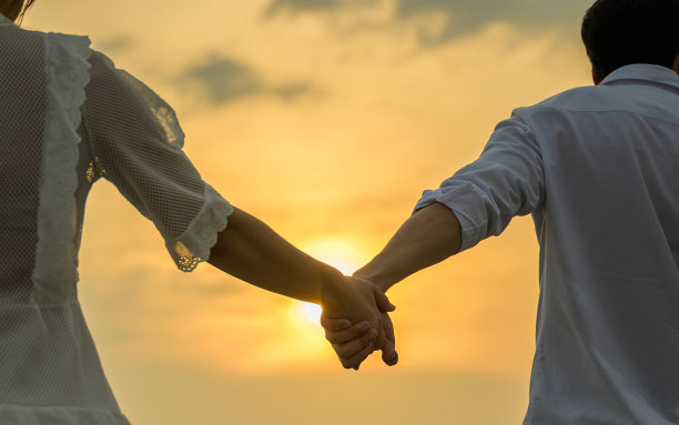 年轻的手牵着散步在傍晚和日落的公园里图片下载