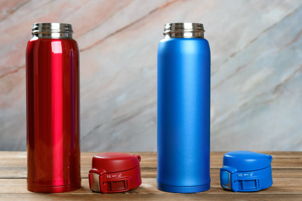 蓝色和红色的真空杯，盖子打开放在木桌上图片下载
