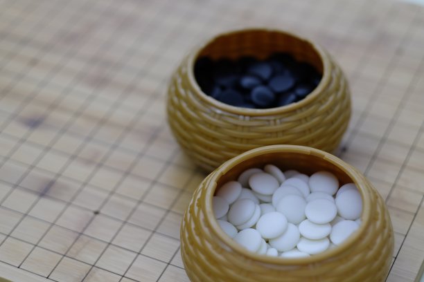靠近白色和黑色的围棋(围棋)石头在木制棋盘上的盒子。图片下载