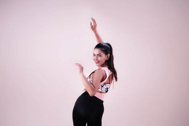 穿着运动服的年轻女子，在空中举起双手，扭动身体，展示舞蹈锻炼的基本模式图片下载
