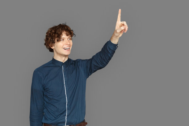 文本或产品的复制空间。十几岁的男孩孤立地站在灰色指着一边笑图片下载