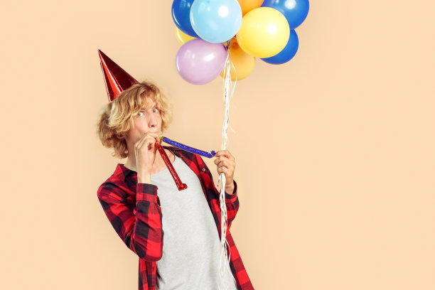 年轻的成年人拿着氦气球庆祝生日，吹着派对号角图片下载