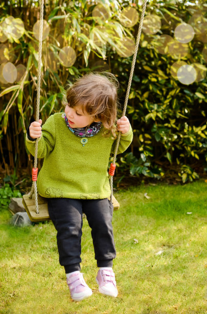 漂亮的小女孩在花园里荡秋千图片下载