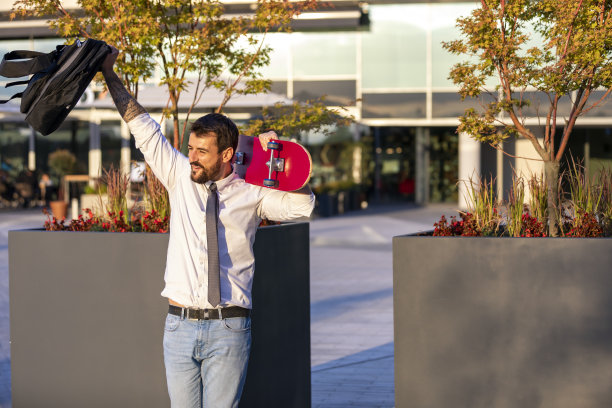 一个穿着西装的年轻人正拿着滑板，手在挥手图片下载