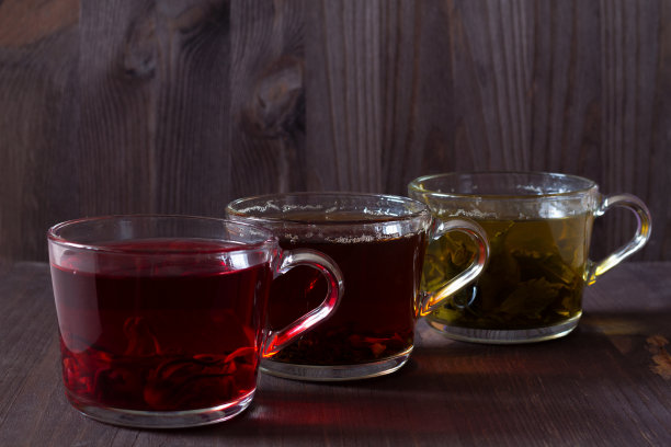 三个杯子，黑色，红色和绿色的茶在一个深色的木制背景。红热芙蓉茶。黑色的热茶。健康的生活方式。热饮料。绿色的热茶放在木桌上。图片下载