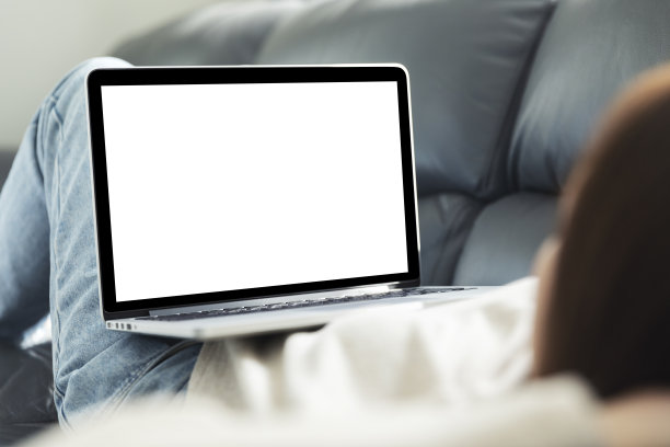 年轻的女人在为她的生意做研究，微笑的女人在沙发上放松，浏览网上购物网站，女人在沙发上使用笔记本电脑，黑屏。图片下载