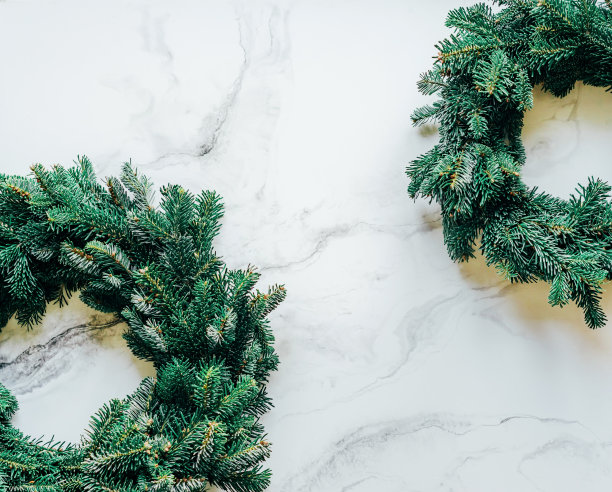 在简单的大理石背景下，两个由天然冷杉树枝制成的圣诞花环的边缘。图片下载
