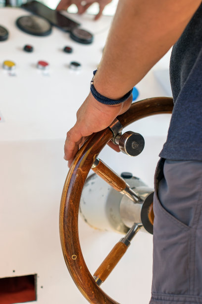 人掌舵海河船。强壮的男船长的手握着游艇的舵柄。图片下载