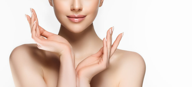 裸露的肩膀，优雅的手势和温柔的微笑在脸上。女性脸部特写。美容。图片下载