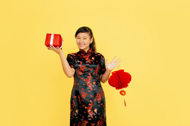 春节快乐。亚洲年轻女孩的肖像孤立在黄色的背景图片下载