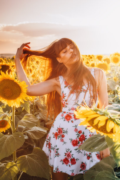 年轻女子在向日葵地里欣赏日落素材图片