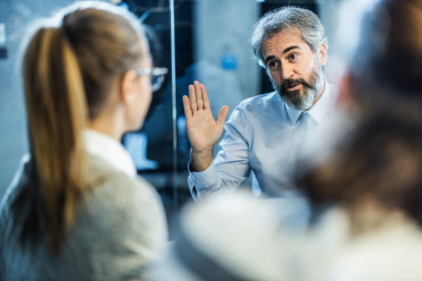 成熟的保险代理人在办公室开会时与客户沟通。素材图片