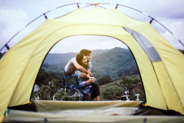 情侣情侣在帐篷外拥抱，开心地微笑，享受露营图片下载