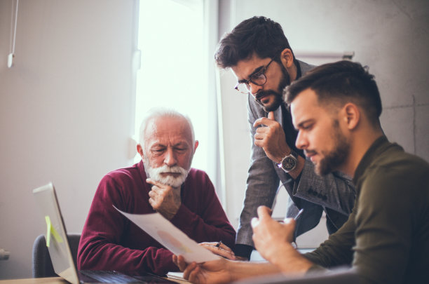 三个商人在办公室里看打印在纸上的报告时，看起来很担心。他们不太喜欢他们所看到的和所想的。图片下载