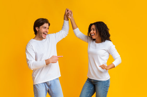 在黄色的背景下，两个人手牵着手一起跳舞图片下载