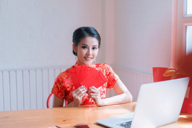 亚洲华人妇女穿着传统旗袍，拿着很多红包送礼物。庆祝中国新年的概念图片下载