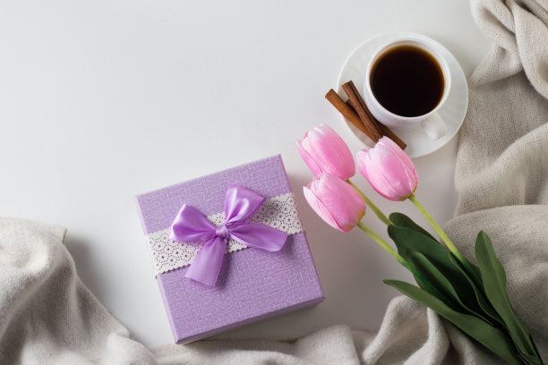 咖啡杯，肉桂，围巾，郁金香，白色背景上的礼盒。春天的概念。平躺，俯视图图片下载