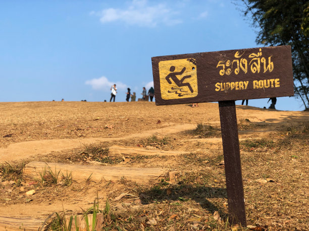 警告标志为“湿滑路线”在山黄色文字和标志上的棕色标签。图片下载