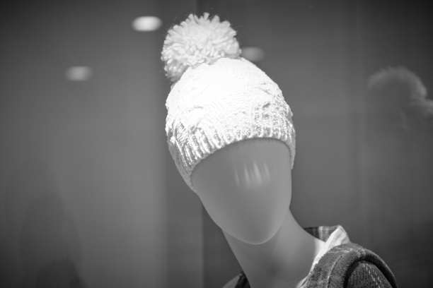 一张黑白照片，一个戴着帽子的半身像模特，背景是灰色。图片下载