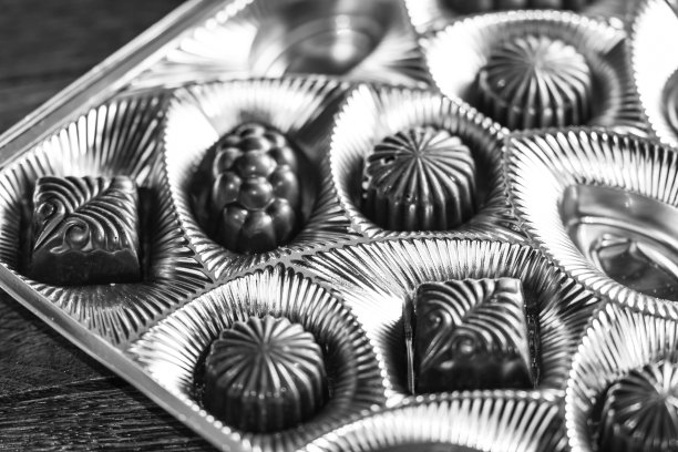 各种美味的巧克力果仁在一个金色的盒子。棒棒糖特写，选择性聚焦。图片下载