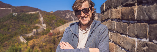 快乐，快乐，快乐的游客在中国长城享受旅游的乐趣，在亚洲度假旅行期间微笑，大笑和跳舞。男子参观和观光中国目的地旗帜，长格式图片下载