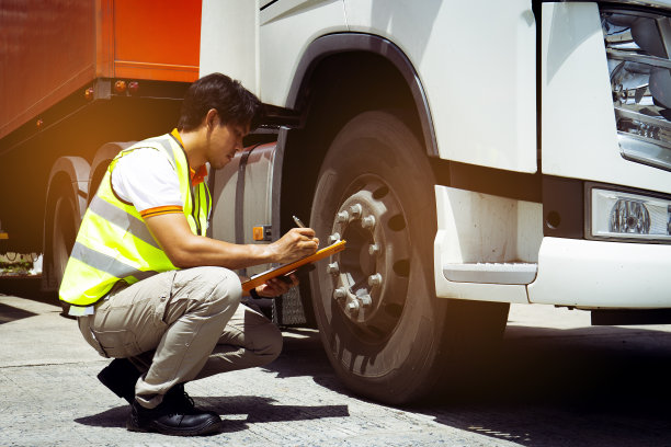 卡车司机亚洲人拿着夹板检查卡车轮胎的安全维护检查表。图片下载