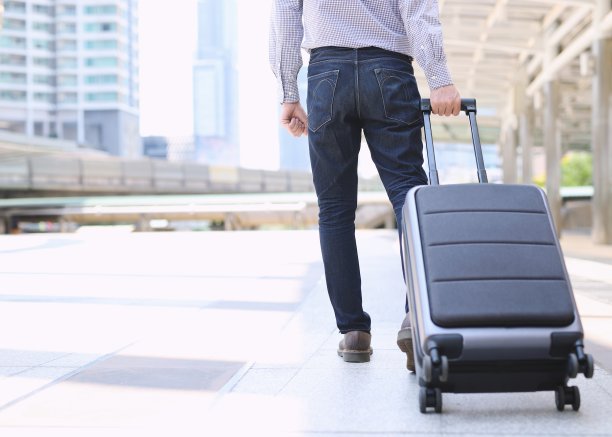 一个年轻的商人拖着旅行袋坐上了飞机去旅行。图片下载