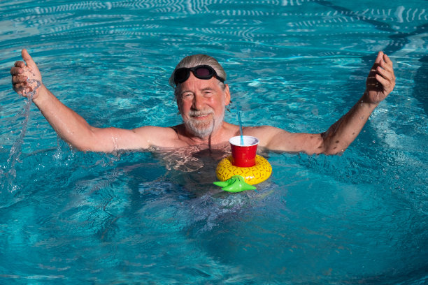 一个高级男子游泳和放松在蓝色游泳池的特写。阳光明媚的一天。白胡子和小胡子。图片下载