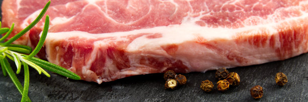 黑石头和木头上的生猪肉排。香料猪肉:迷迭香和胡椒。特写生猪肉排。图片下载