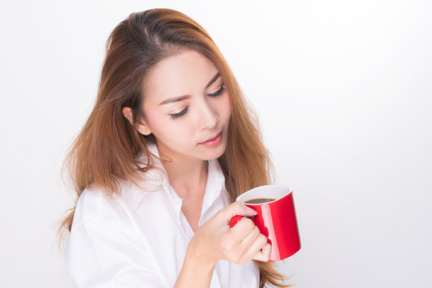 微笑的女人拿着红色的咖啡杯。图片下载