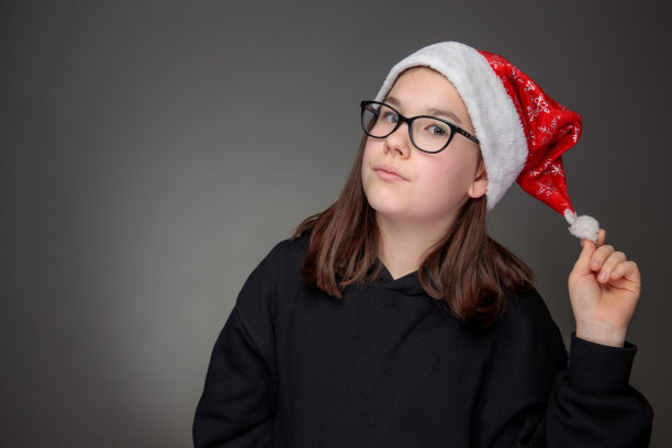 少女长头发，红色圣诞老人帽，黑色运动衫和眼镜图片下载